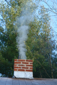 Metal chimney with brown brick & smoke coming out of it