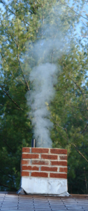 Brown brick chimney with smoke coming out of it